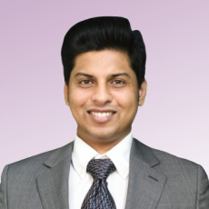 Kaushik Muniandi, an Engineering Manager at NielsenIQ. He is wearing a gray suit, a white shirt, and a patterned tie. He has short, dark hair and is smiling against a light purple background.