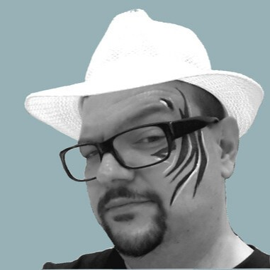 A man wearing glasses and a white hat with black face paint on one side of his face.