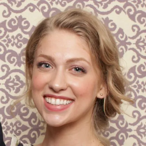 A woman with blonde hair and blue eyes smiling.